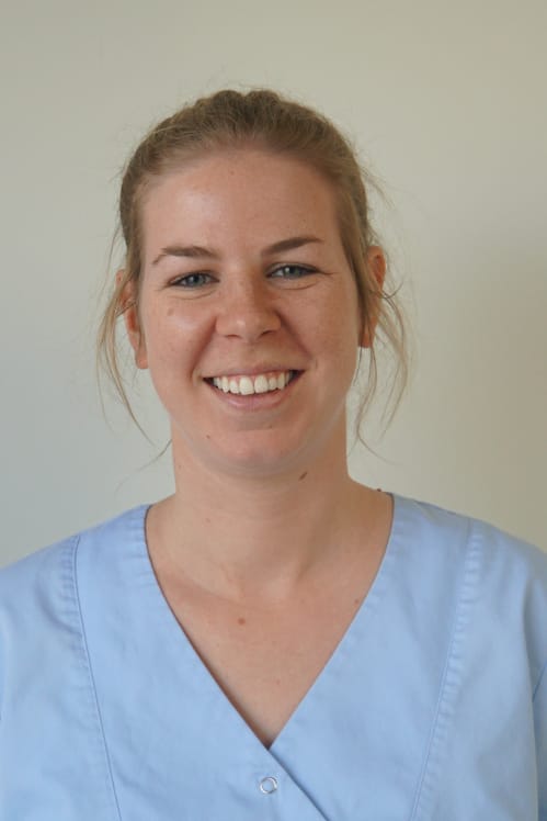 Tandarts Ellen Rijckaert in een witte medische tuniek met halflang kastanjebruin haar